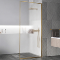 Glass shower door with gold frame in a bathroom setting