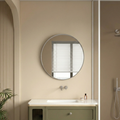 Bathroom with round mirror, sink, and vanity unit on a beige wall.