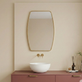 Bathroom vanity with a white sink, gold fixtures, and a large mirror on a beige wall.