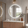 Bathroom with round illuminated mirror, wooden vanity, and decorative elements.