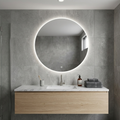 Modern bathroom vanity with round illuminated mirror and gray tiles.