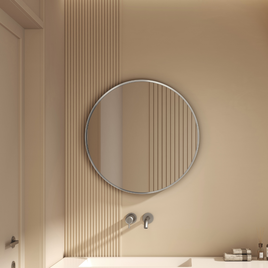 Round mirror on a beige wall with a bathroom setting