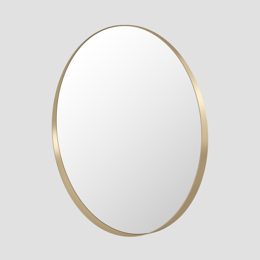 Round mirror with a gold frame on a light gray background